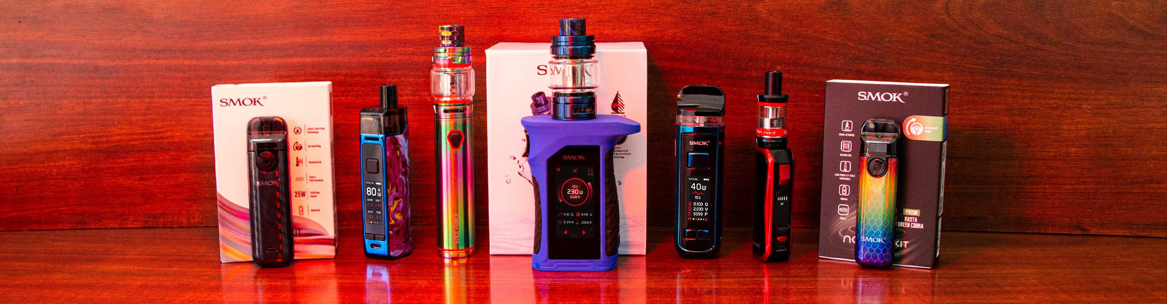 Got Vape Retail SMOK products lined up standing on wooden table with wood background under red lighting